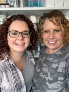 Our salon owner and salon apprentice in front of curly hair products