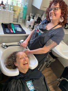A salon client and stylist laughing during a haircut