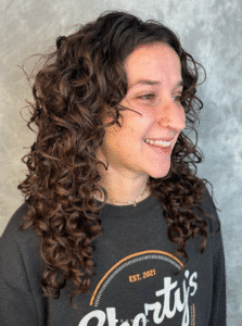 Woman with a curly shag haircut smiling.